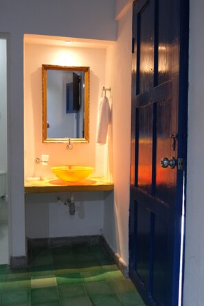 Une salle de bain avec un lavabo jaune, un miroir et une porte bleue.