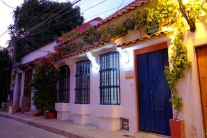 Un bâtiment avec une porte bleue, une enseigne indiquant « Lodo » et une petite fenêtre ornée d’une grille métallique.