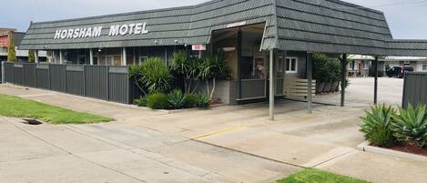 Un motel con un letrero que dice 'HORSHAM MOTEL' y un letrero de 'HABITACIONES DISPONIBLES'.