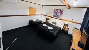 A hotel room with two beds, a wooden ceiling, a window with blinds, a painting on the wall, and a desk with a chair. - Horsham Motel (Horsham)