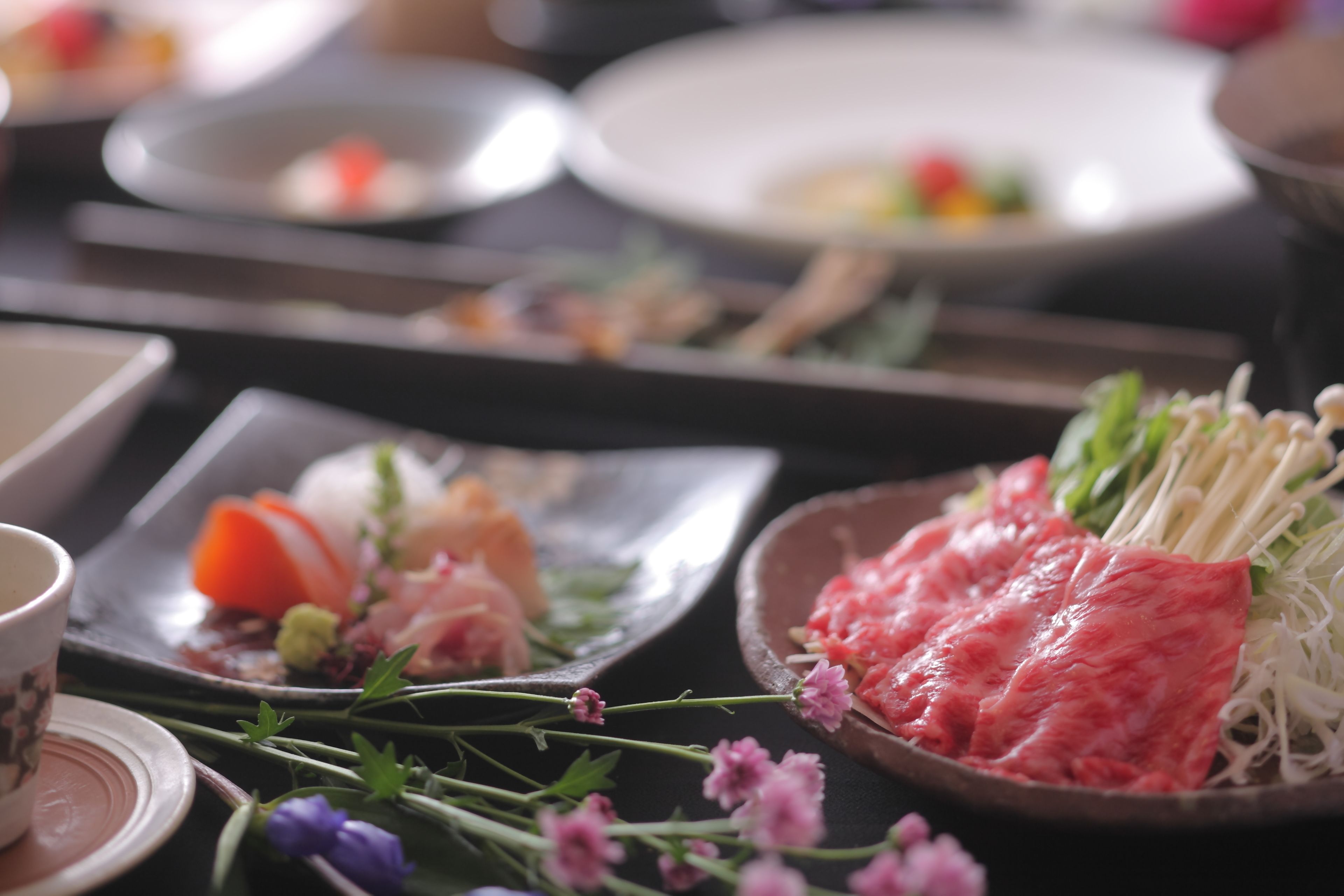 A dining table with various dishes, including sashimi and fresh vegetables.