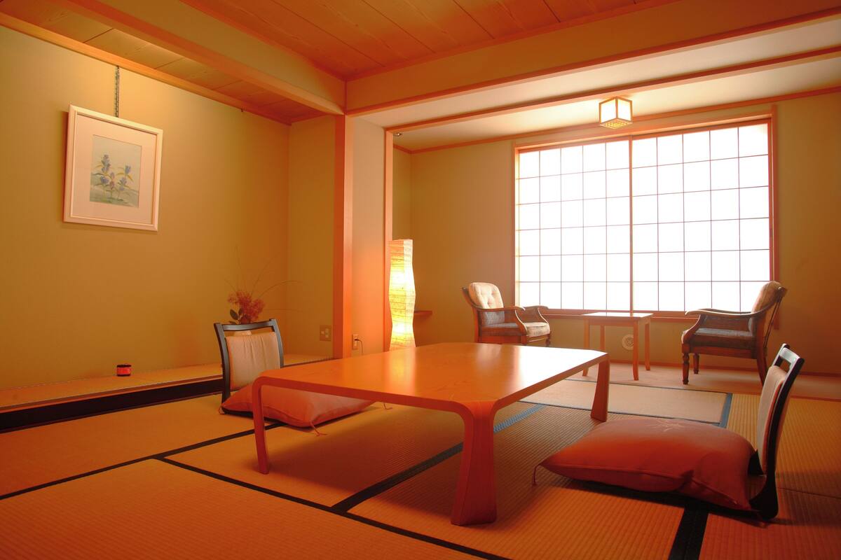 Een traditionele Japanse kamer met tatami vloerbedekking, een lage tafel en twee stoelen.