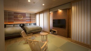 Een moderne hotelkamer met twee bedden, een televisie, een kleine tafel en een zithoek.