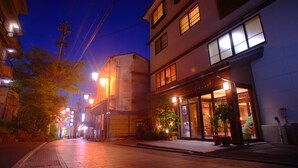 Een traditioneel Japans gebouw met een goed verlichte entree, grote ramen en potplanten.