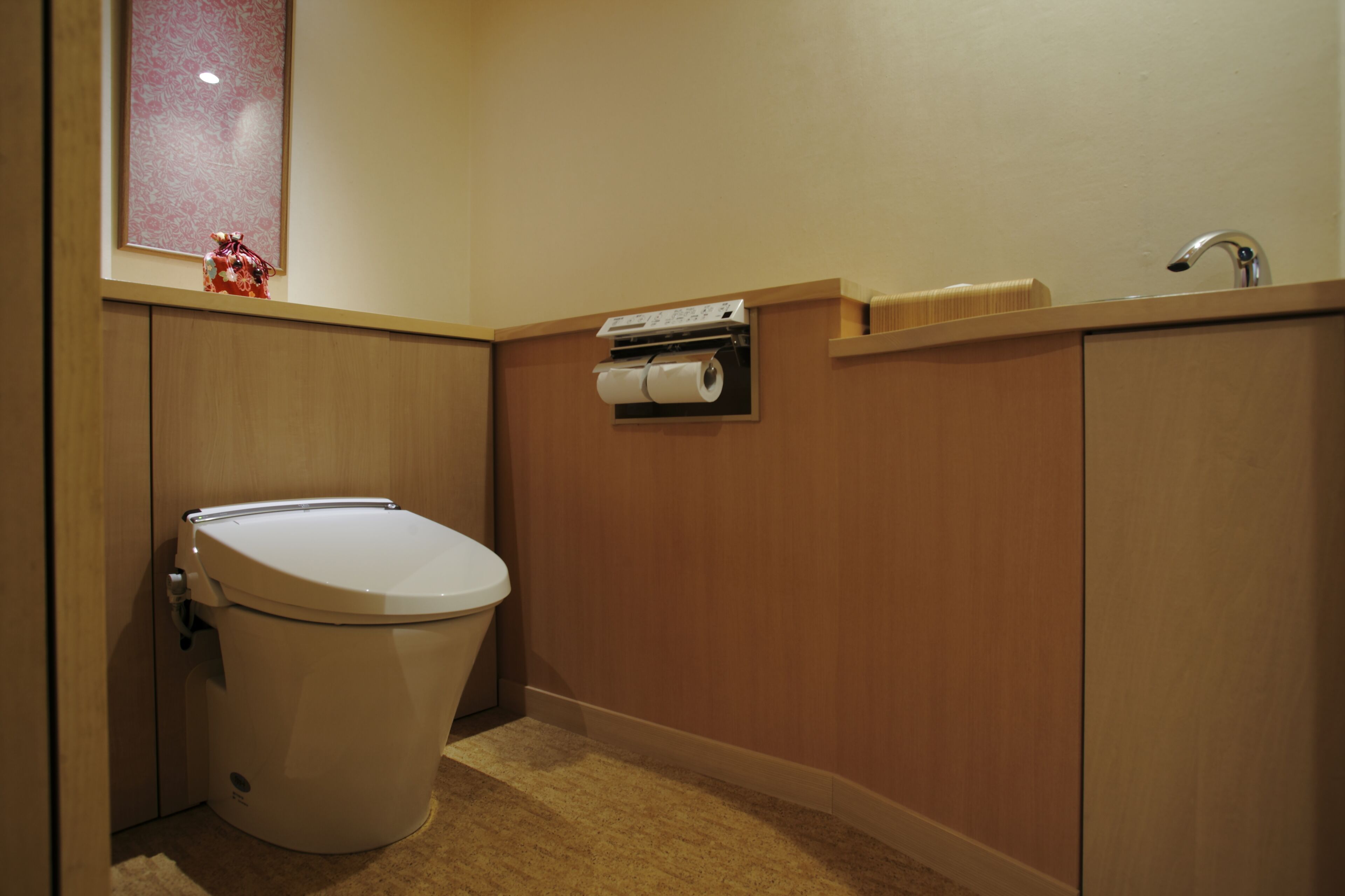 A small, compact bathroom with a toilet, a sink, and a paper towel dispenser.