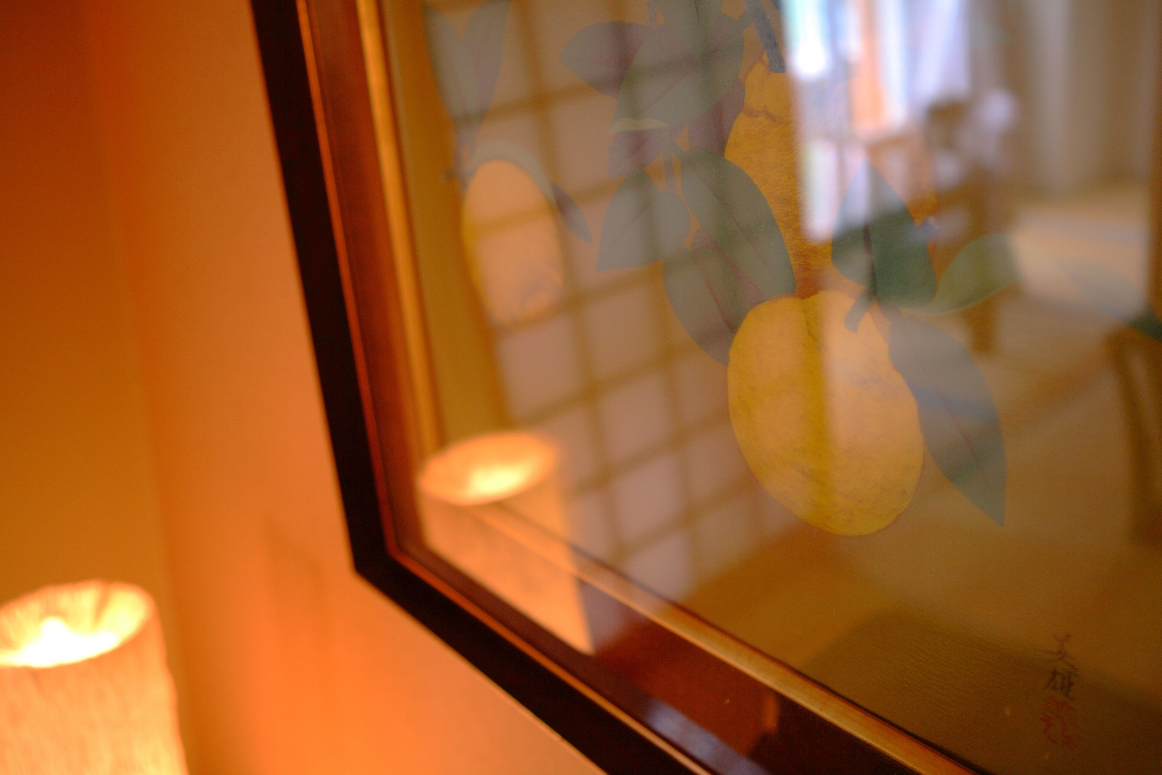 Primer plano de una ventana que refleja el interior de una habitación, con una lámpara y una silla.