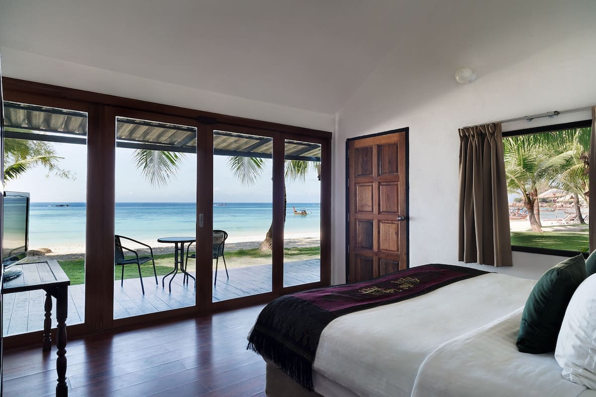 Ein Schlafzimmer mit einer großen Schiebeglastür, die auf einen Balkon mit Blick auf den Strand führt.