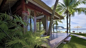 A wooden deck with a bench, surrounded by lush greenery and palm trees, overlooking a body of water. - Mali Resort Pattaya Beach Koh lipe (Koh Lipe)