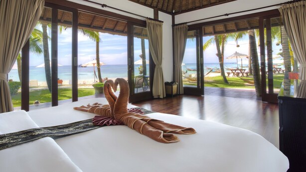 A hotel room with a large bed, a view of the beach, and a thatched roof. - Mali Resort Pattaya Beach Koh lipe (Koh Lipe)