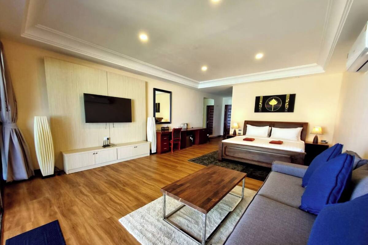 Ein Hotelzimmer mit Bett, Sofa, Fernseher, Schreibtisch und Spiegel.