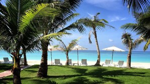 A beachside area with palm trees, white lounge chairs, and umbrellas. - Mali Resort Pattaya Beach Koh lipe (Koh Lipe)