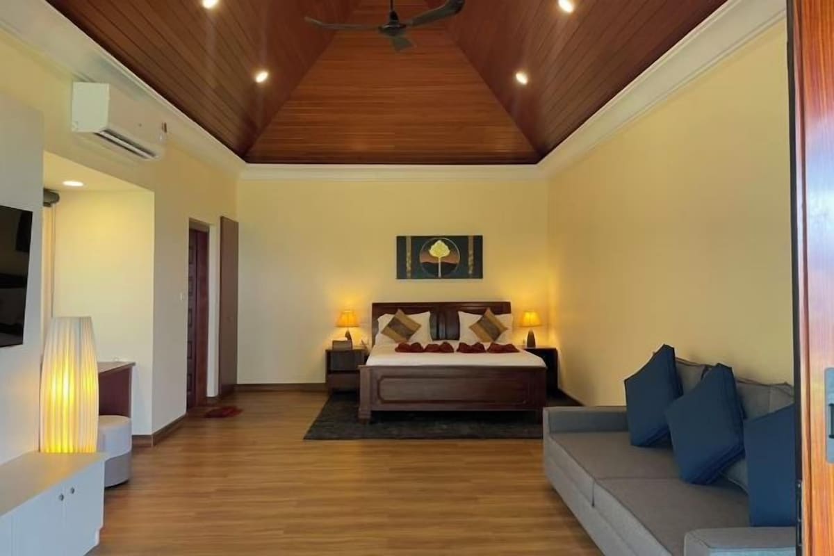 A bedroom with a bed, bedside tables, a television, and a ceiling fan.