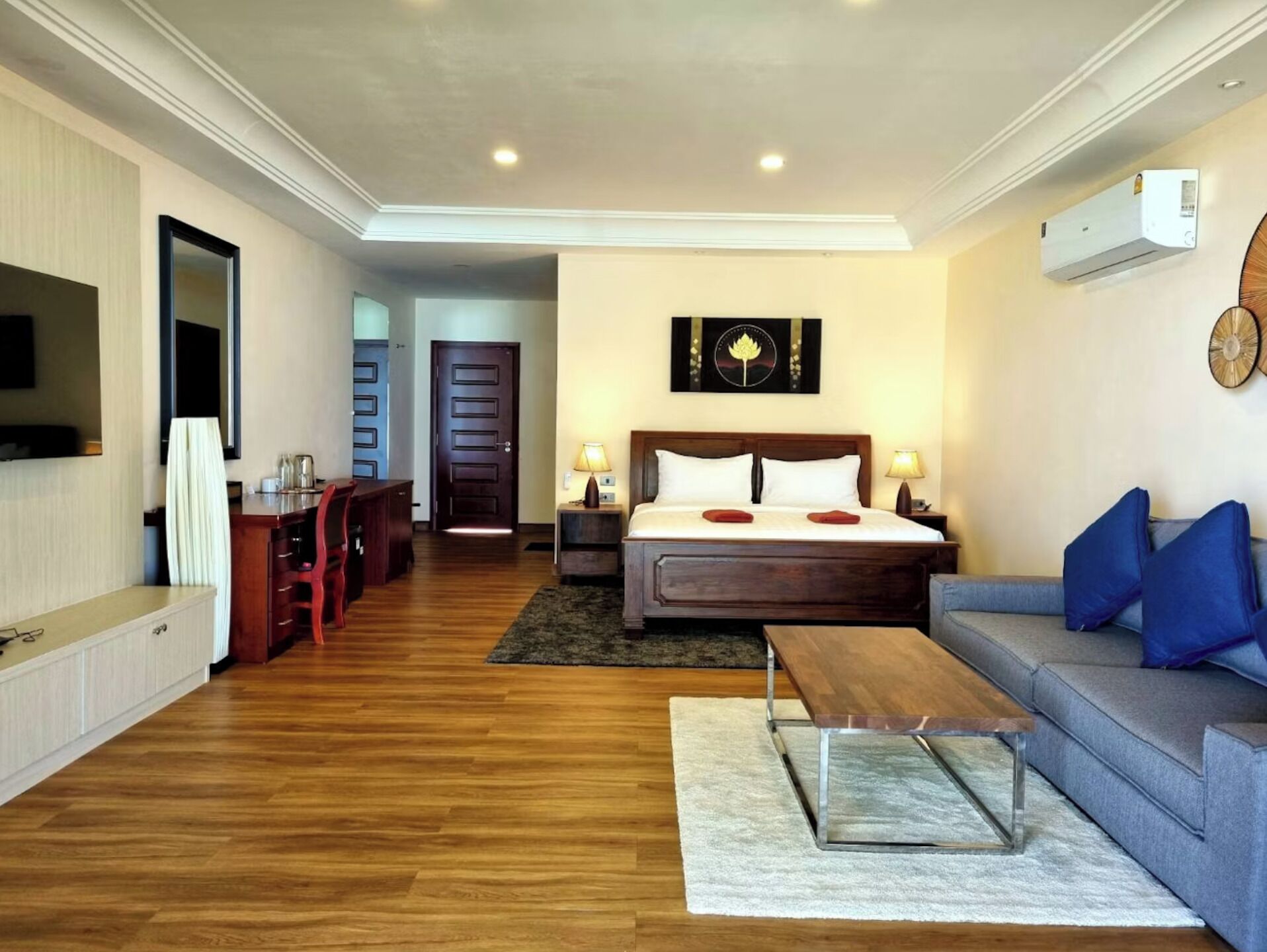 Une chambre d’hôtel comprenant un lit, un canapé, une table basse, un bureau et un téléviseur.