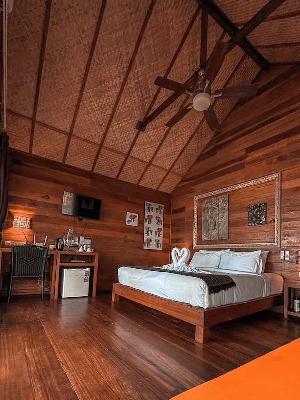 A wooden cabin-style bedroom with a bed, desk, chair, and a ceiling fan. - Ten Moons Lipe Resort (Koh Lipe)