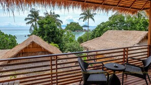 A thatched-roof structure with a view of the sea and palm trees.