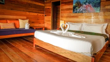 Ein holzgetäfelter Raum im Chalet-Stil mit einem Bett, das mit einer Schwan-Form-Kissenanordnung und einem Waldgemälde dekoriert ist.