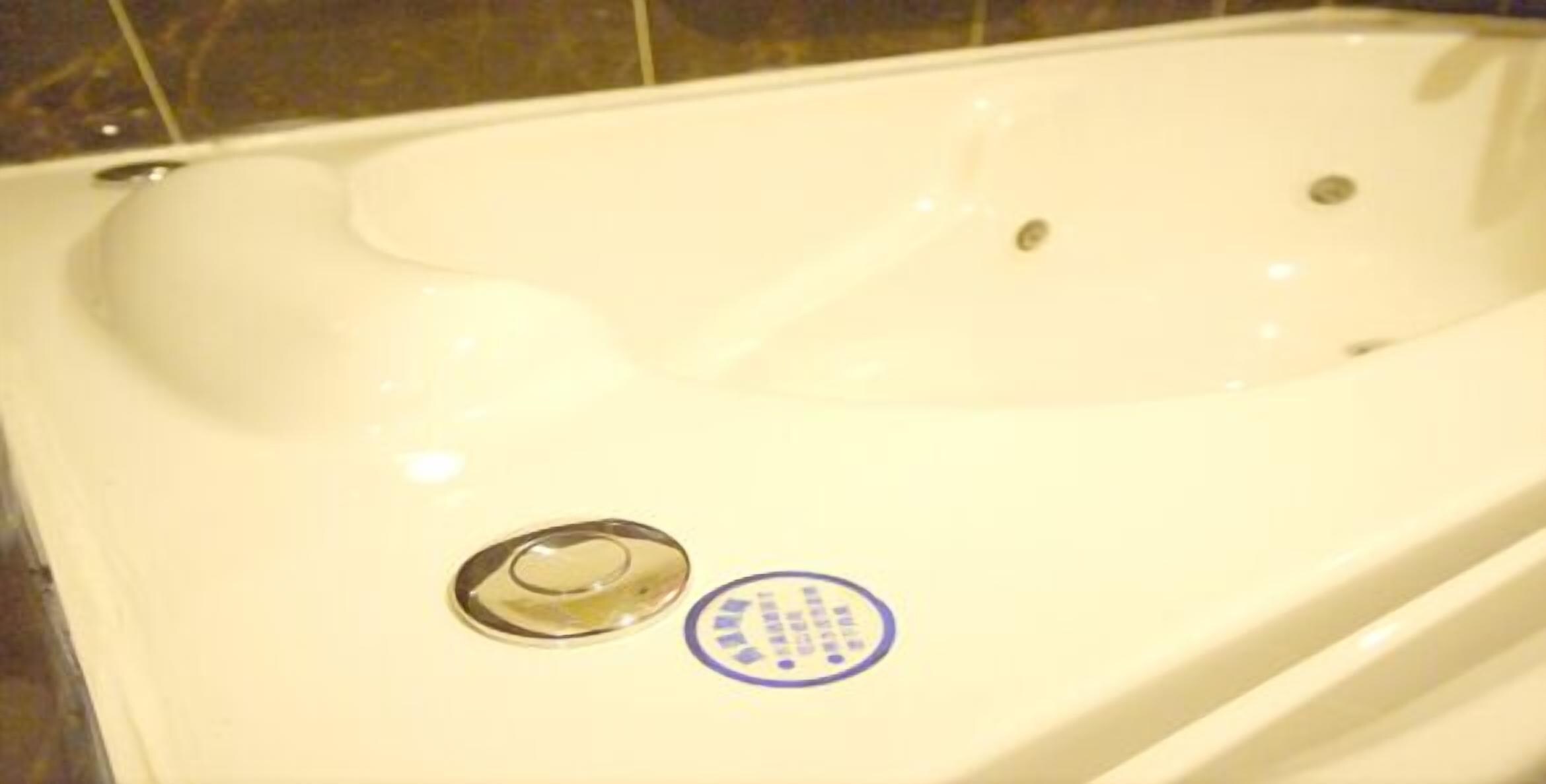 A bathtub with a drain and a control panel.