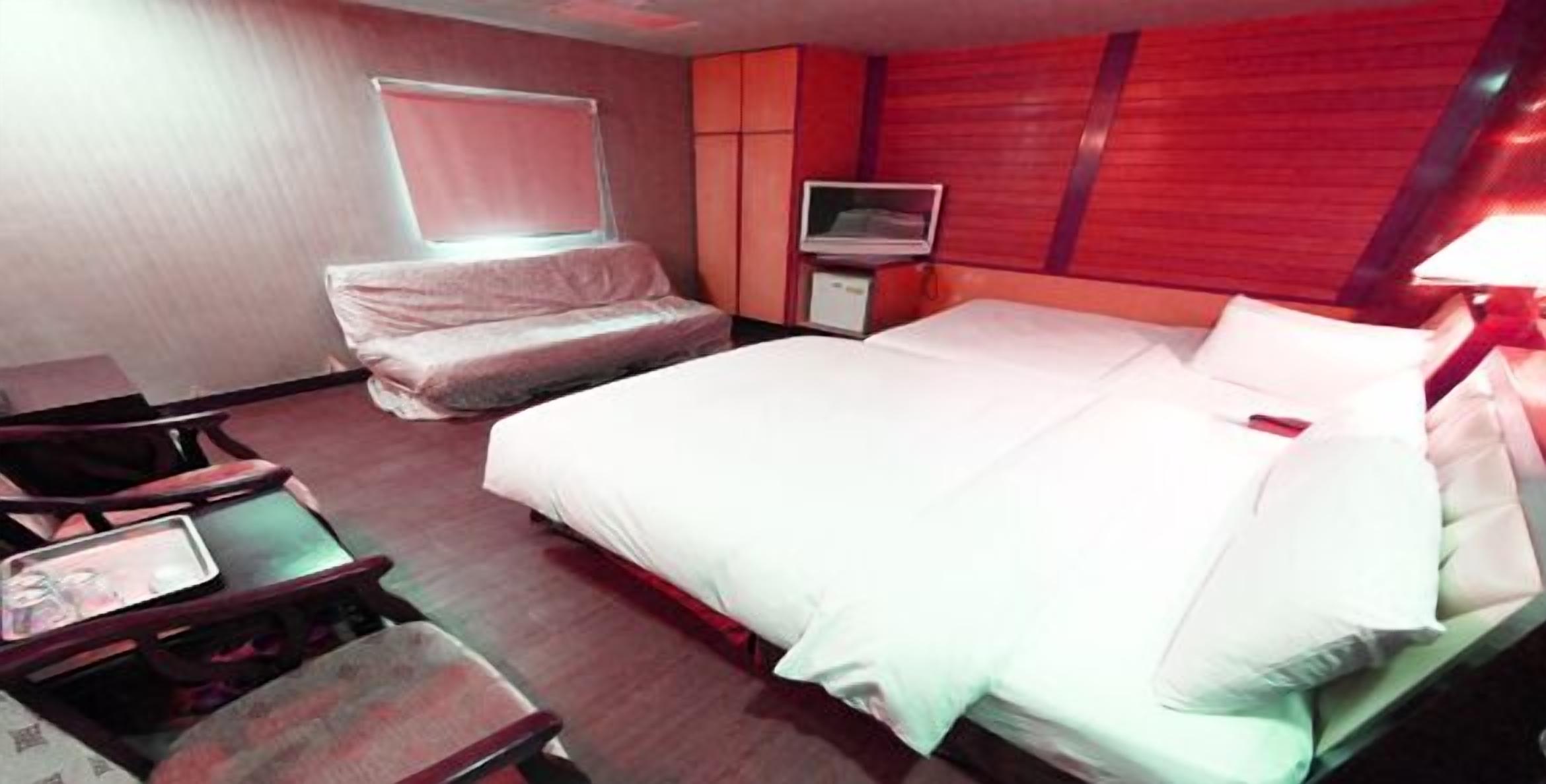 A hotel room with a bed, a TV, a desk, and a chair.