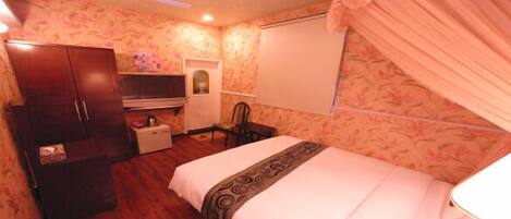 A bedroom with a bed, a wardrobe, a desk, and a chair.