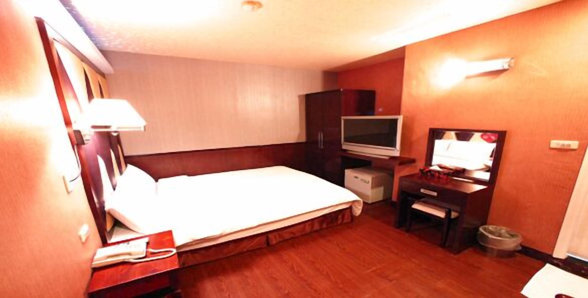 Ein Hotelzimmer mit Bett, Fernseher, Schreibtisch und Kleiderschrank.