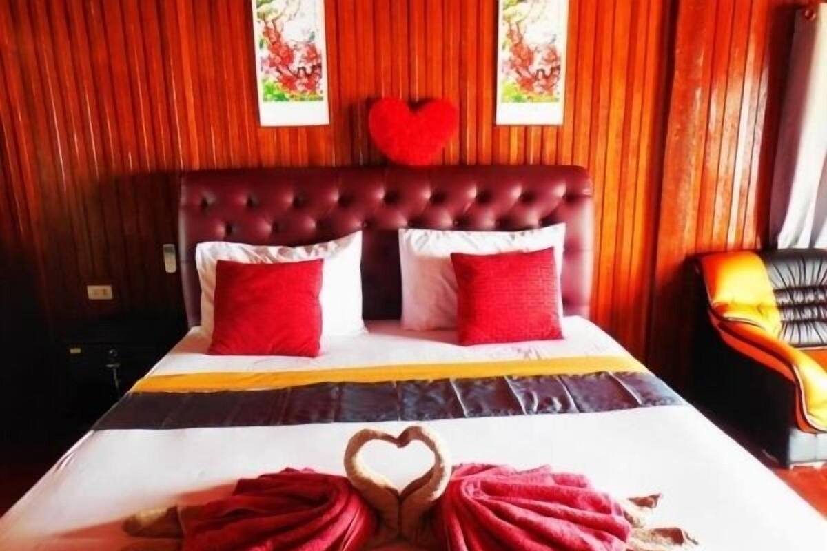 Una habitación de hotel con una cama grande, almohadas rojas y una disposición de toallas con forma de corazón.