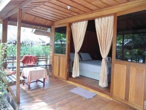 A wooden room with a bed, curtains, and a table with a chair. - Zanom Sunrise Beach Resort (Koh Lipe)