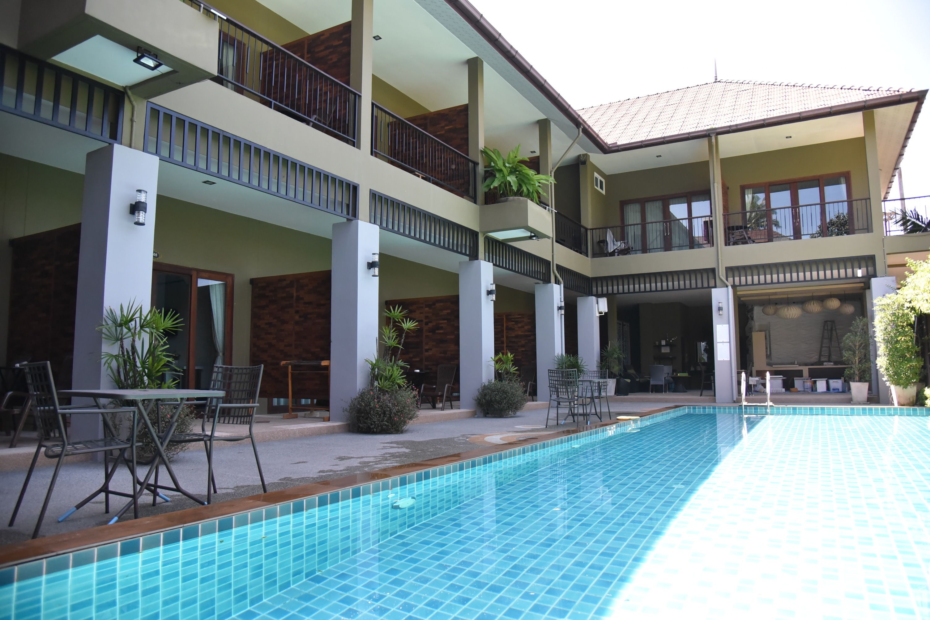 A multi-story hotel with a swimming pool, outdoor seating, and balconies.