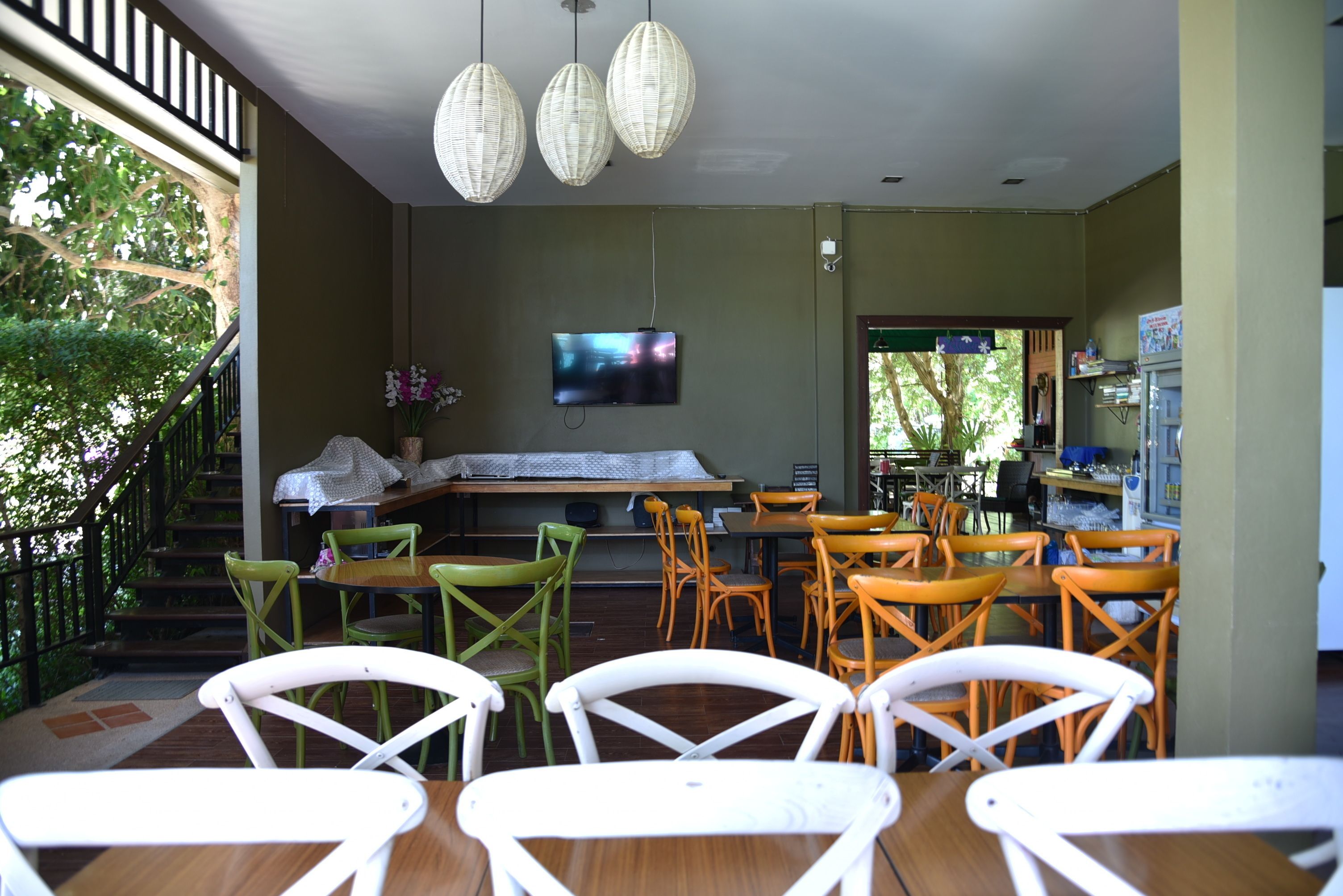 A restaurant with outdoor seating, a TV mounted on the wall, and a staircase leading to an upper level.