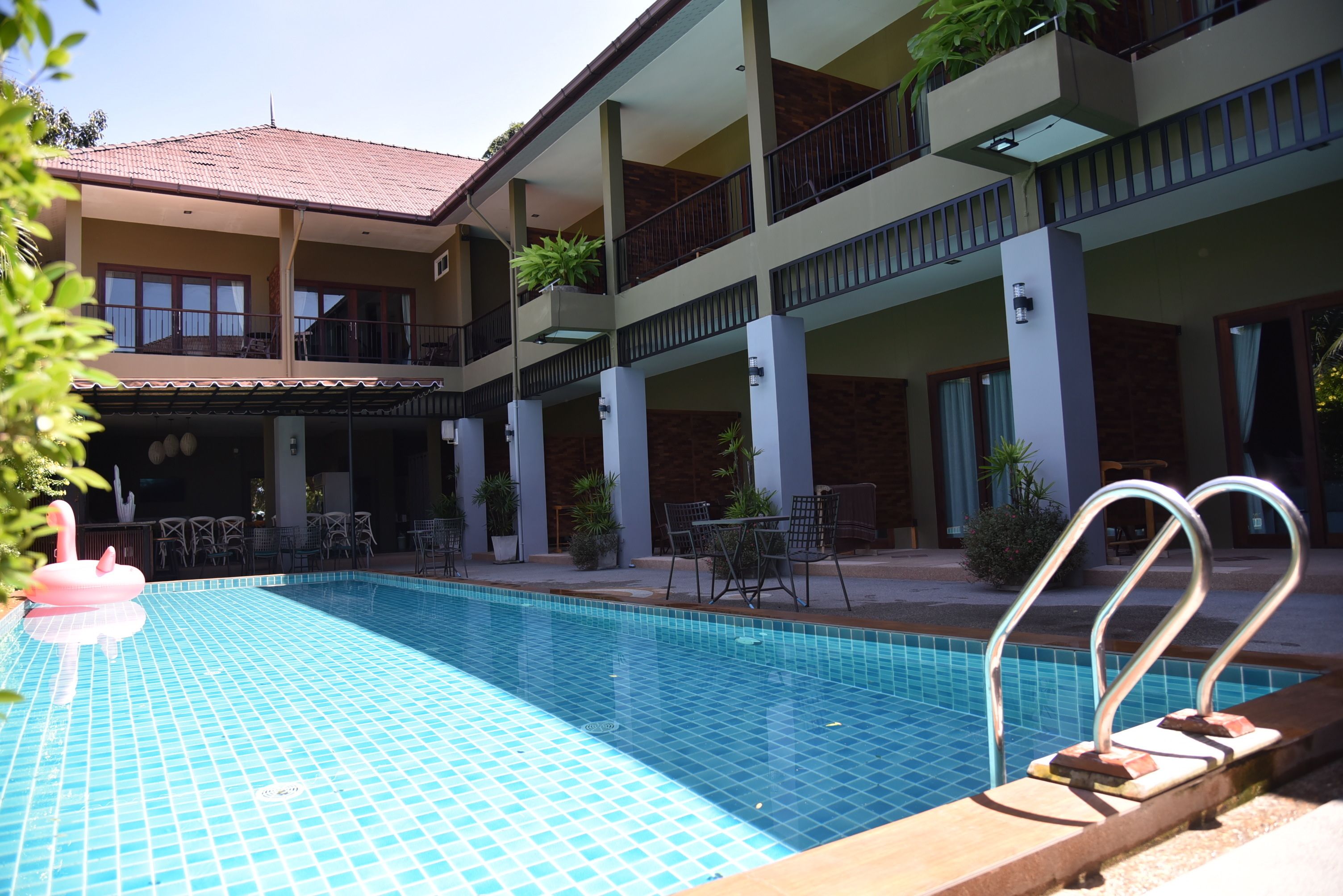 A swimming pool with a tiled floor, surrounded by outdoor seating and potted plants.