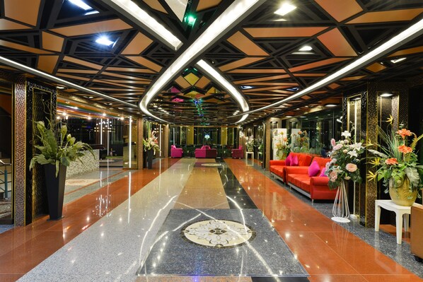 A spacious lobby with a polished floor, a central seating area, and modern lighting fixtures.