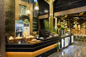 Eine moderne Hotelhalle mit einem Marmor-Rezeptionsschalter, einer Kaffeemaschine und einem mit Getränken gefüllten Kühlschrank.