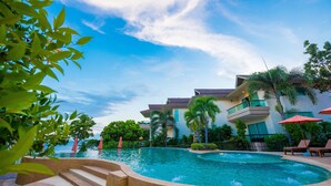 A swimming pool with steps leading into it, surrounded by palm trees and lounge chairs.