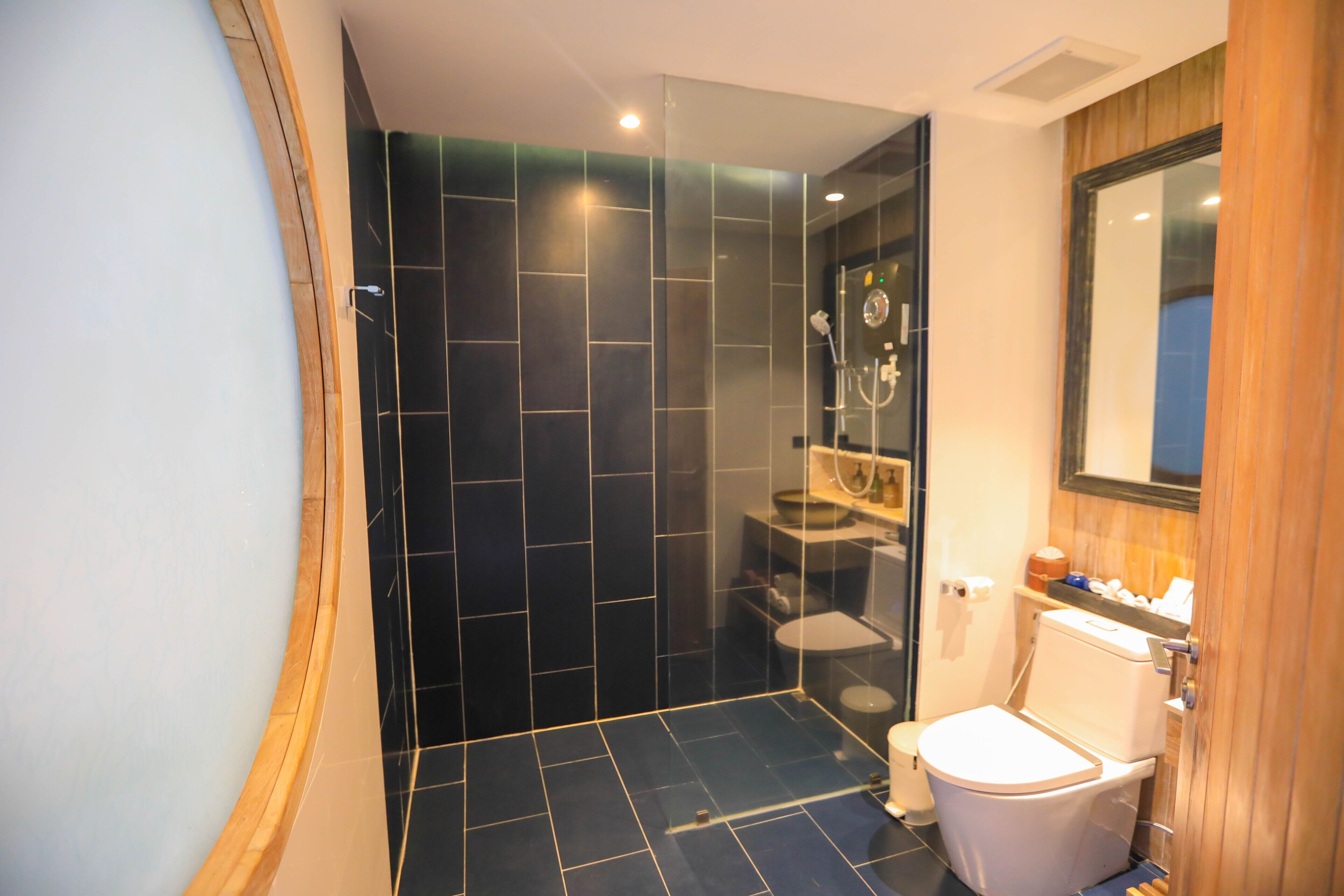 Un baño moderno con cabina de ducha de vidrio, inodoro blanco y tocador de madera.