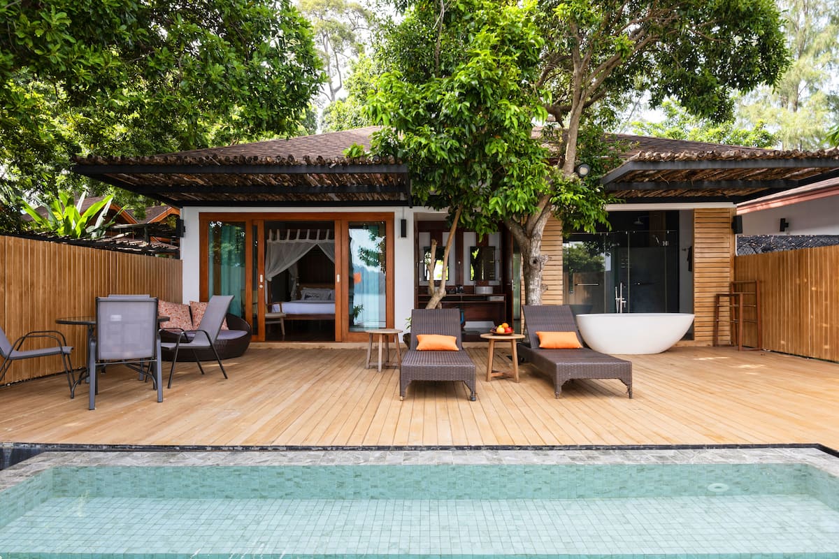 Una terraza de madera con piscina, sillas de descanso y bañera de hidromasaje.