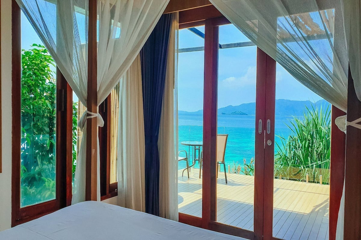 Un dormitorio con un ventanal grande, una cama y vistas al mar.