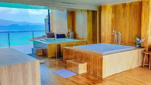 A wooden deck with a large bathtub and a sink, overlooking a body of water. - The Cliff Lipe (Koh Lipe)