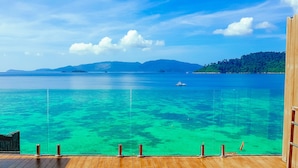 A wooden deck with glass railings overlooking turquoise waters, distant islands, and a clear sky. - The Cliff Lipe (Koh Lipe)