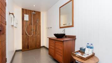 A bathroom with a wooden door, a sink with a black basin, a mirror, and a small table with toiletries.
