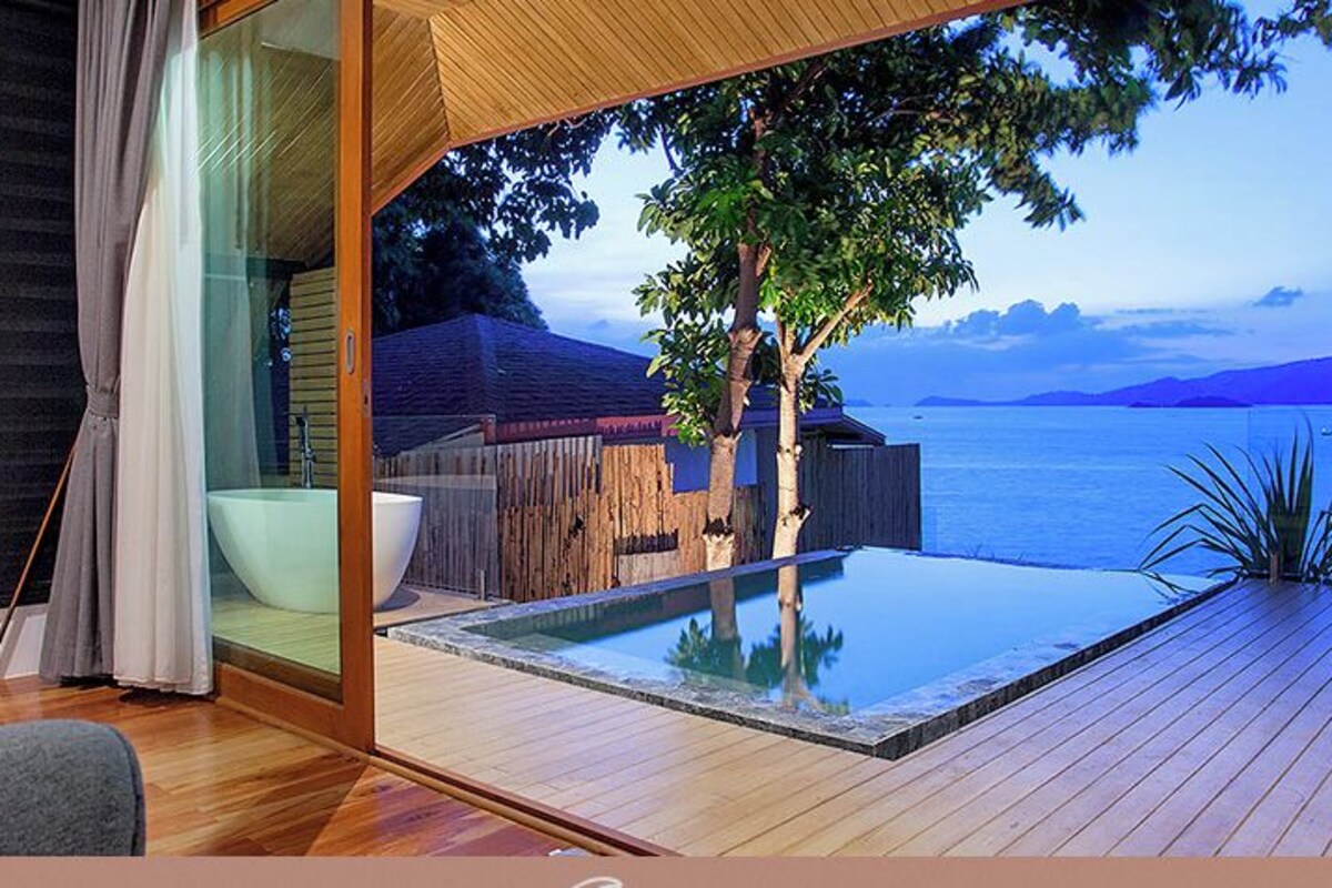 En modern villa med en glasdörr som leder ut till en privat pool och en vacker utsikt över havet.