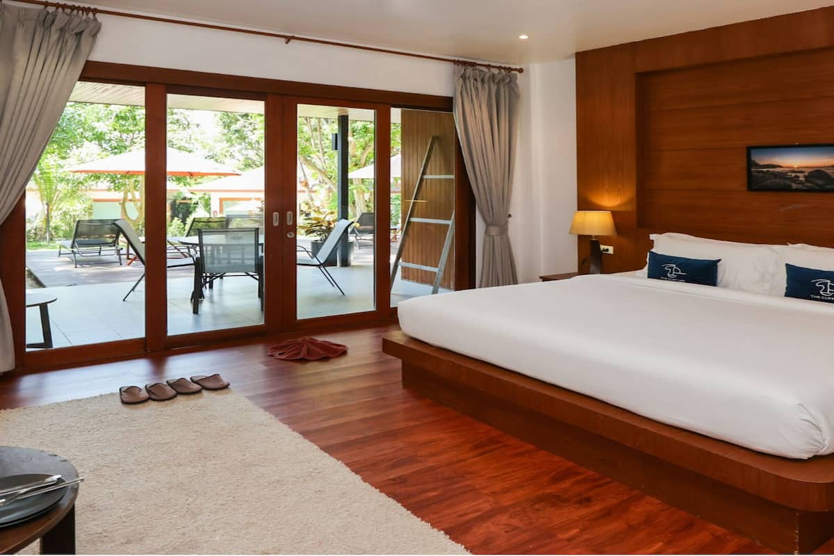 Un dormitorio amplio con una cama grande, cabecero de madera y vista al patio exterior.