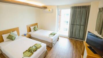 A hotel room with two beds, a TV, and a window with curtains.