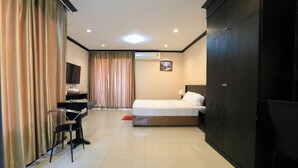 A hotel room with a bed, a desk with a chair, a TV, and a wardrobe.