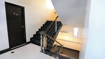 A modern staircase with a black railing and a door labeled "T35".