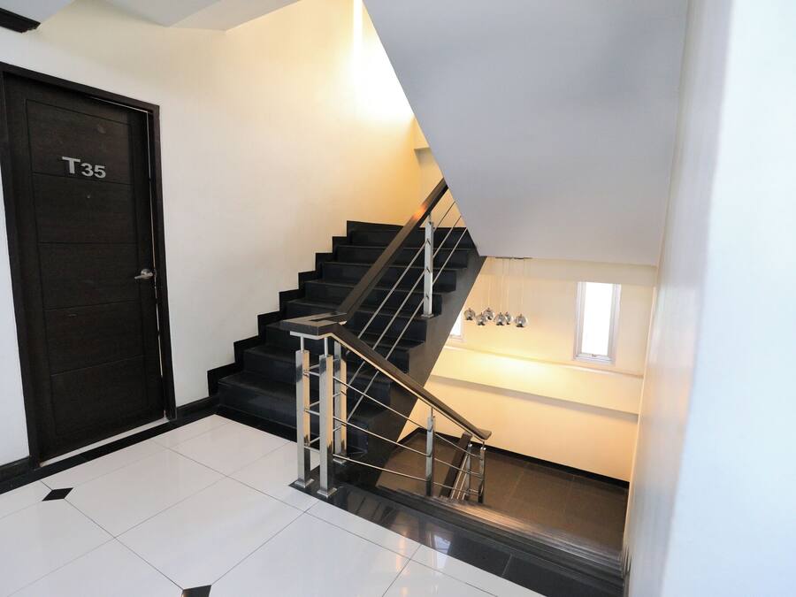 A modern staircase with a black railing and a door labeled "T35".