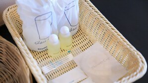A wicker basket containing a shower cap, a bottle of shampoo, and a bag labeled 'Glass Steril'.