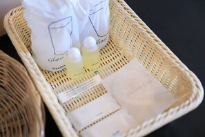 A wicker basket containing a shower cap, a bottle of shampoo, and a bag labeled 'Glass Steril'.