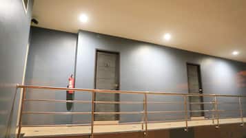 A staircase with a metal railing, a fire extinguisher mounted on the wall, and two doors.