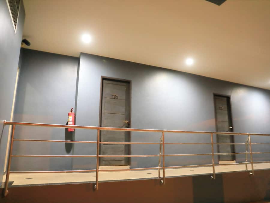 A staircase with a metal railing, a fire extinguisher mounted on the wall, and two doors.