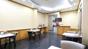 A hotel lobby with a reception desk, seating area, and a television screen.