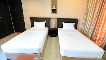 A hotel room with two beds, a nightstand with a lamp, a mirror on the wall, and a red rug on the floor.